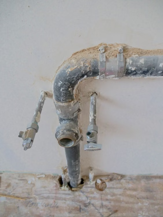 Exposed metal plumbing pipes installed along a residential construction wall.