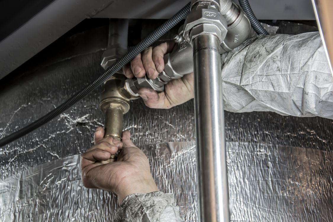 Plumber installing steel pipe fittings during a residential plumbing repair.