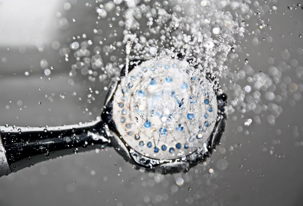 Water flowing from a showerhead affected by hard water mineral deposits.