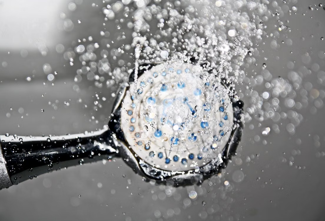 Water flowing from a showerhead affected by hard water mineral deposits.