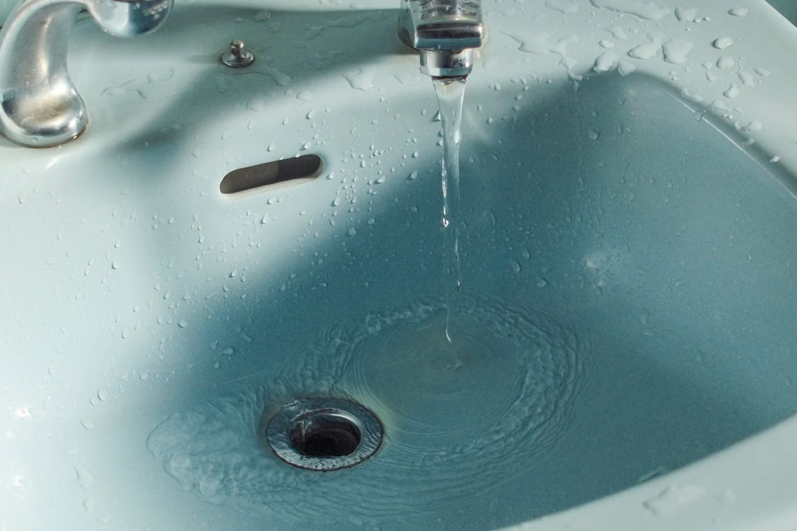 Water flowing into a bathroom sink drain during everyday use.